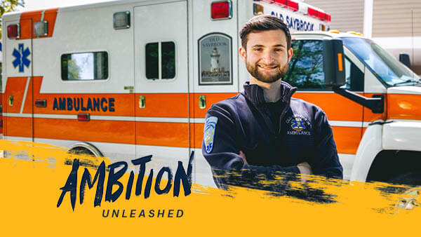 Charles Dunn dressed as an EMT stands in front of an ambulance