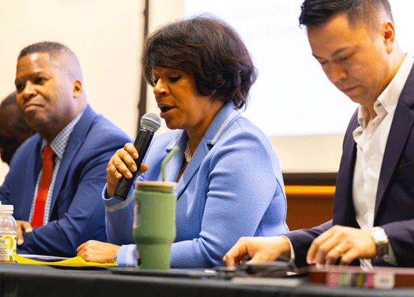 Panelist talking into a microphone to a crowd