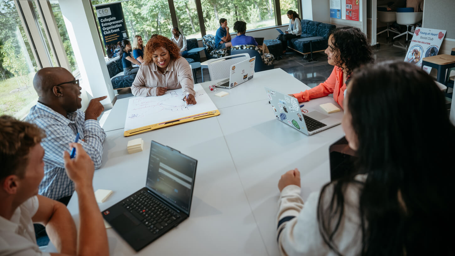Professor of management Robert Mayfield Yawson works with students in a collaborative classroom setting.