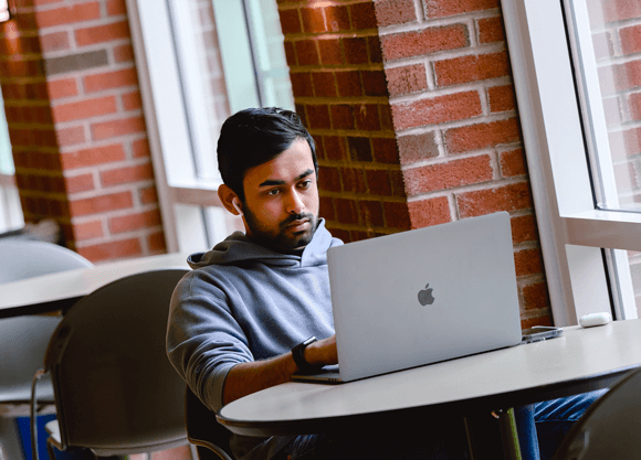Student sitting at a table working on their laptop