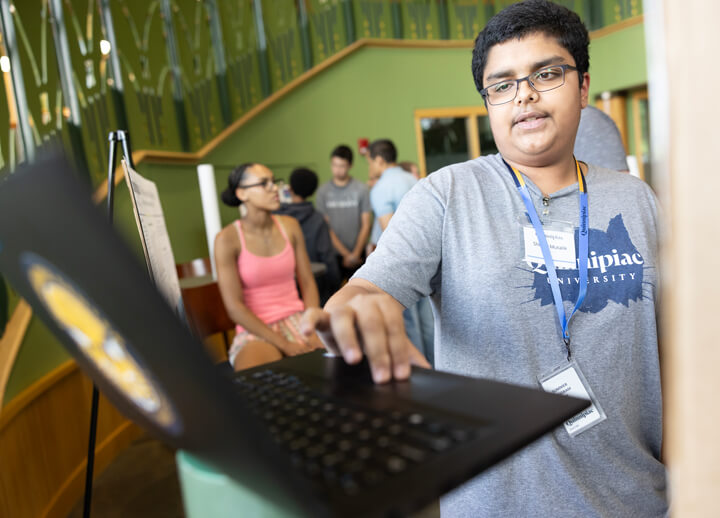 A high school student working on a computer in the piazza during a summer career camp.