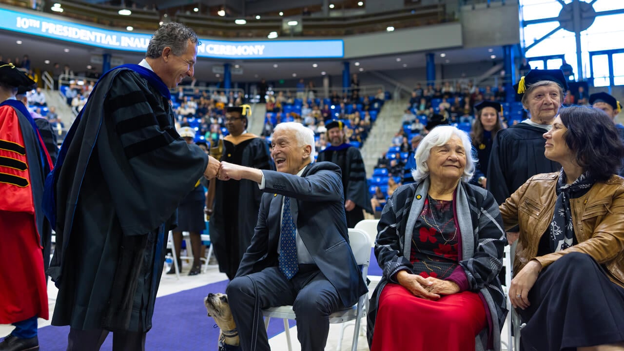 Chuck Saia fists bumps members of Marie Hardin's family seated on the floor of the stadium