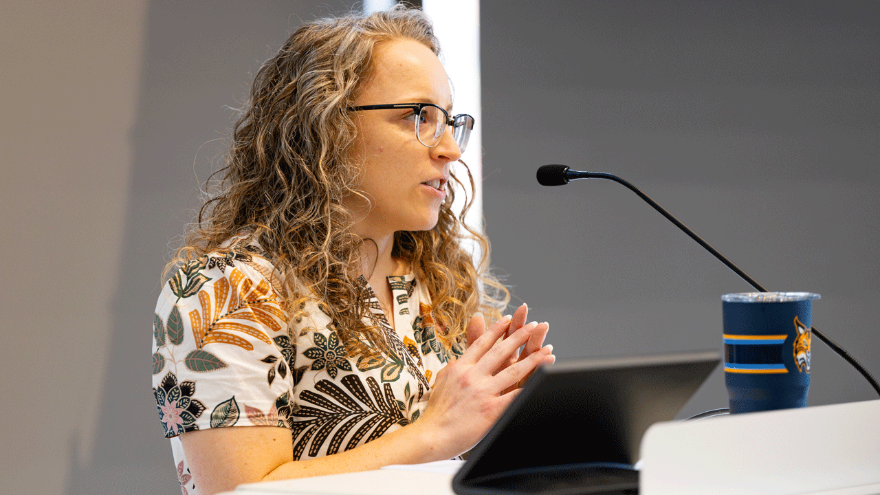 Moderator of the panel talking into the microphone at a podium