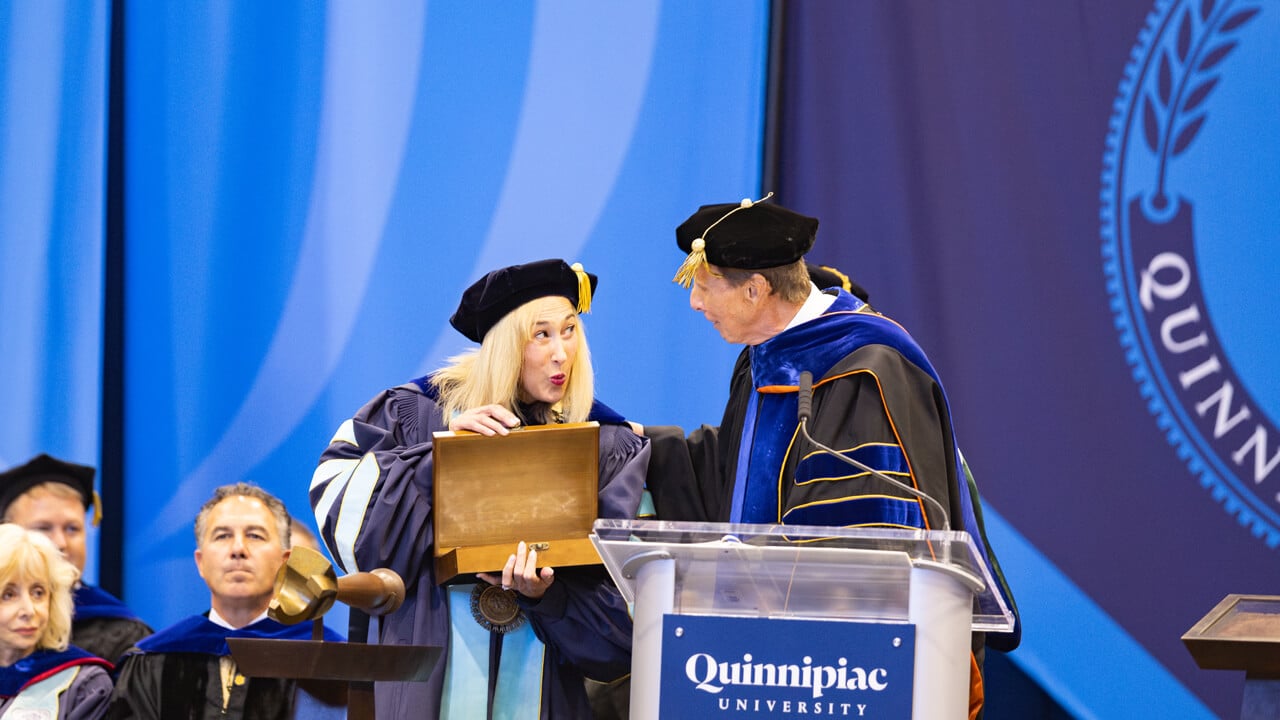 Marie Hardin emoting while holding a ceremonial box with John Lahey
