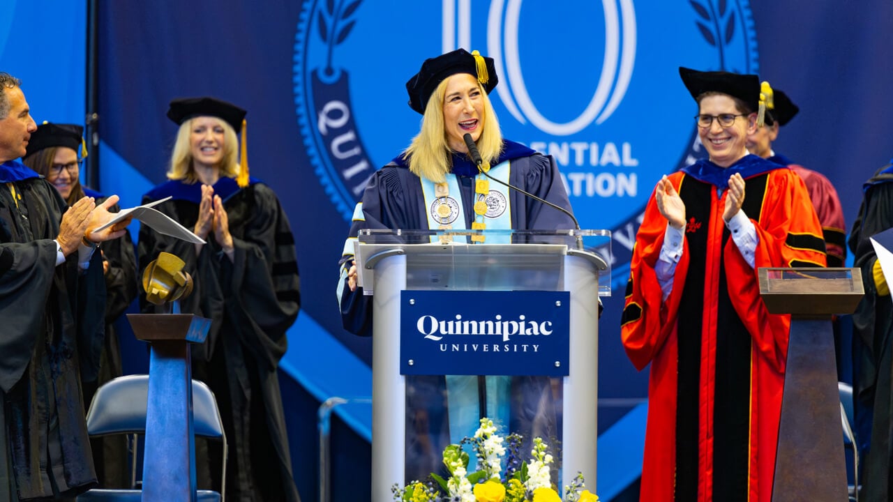 Marie Hardin at the podium while Deb Liebowitz and administrators clap