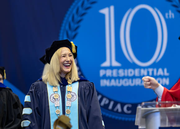 Marie Hardin smiles broadly in her Inauguration robes on stage