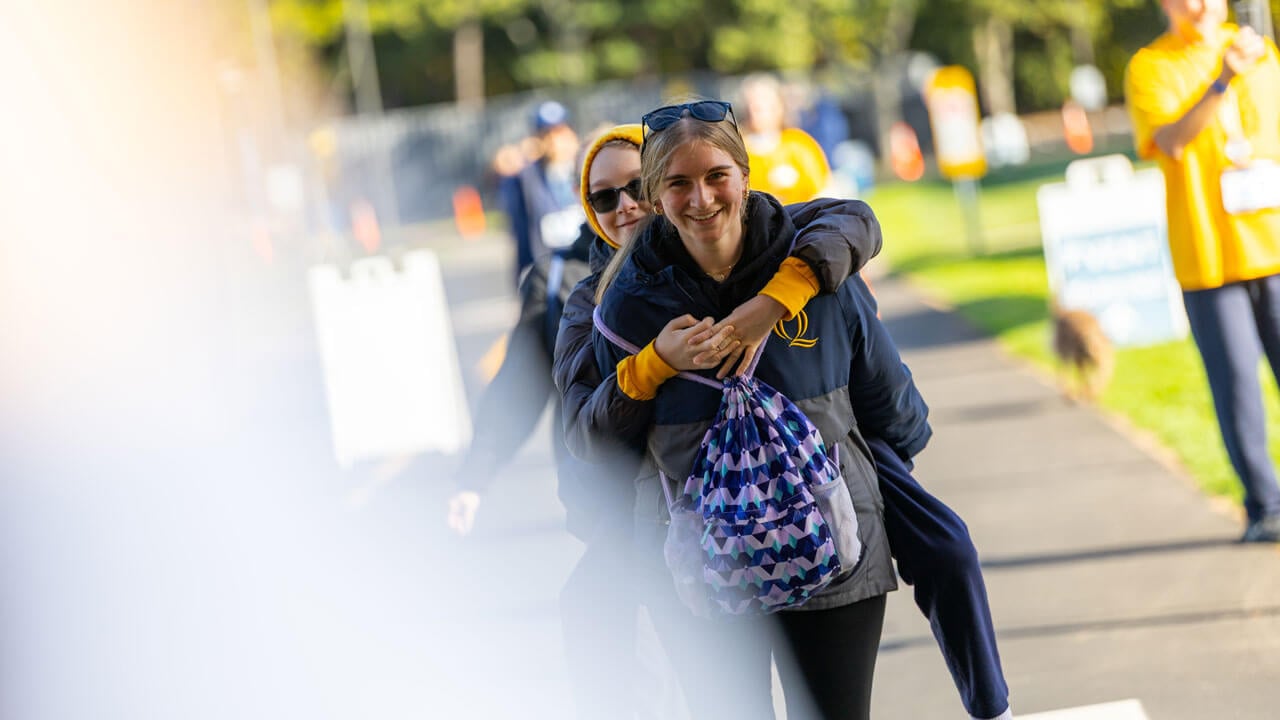 One runner giving another a piggy back ride through the bobcat head to finish the race