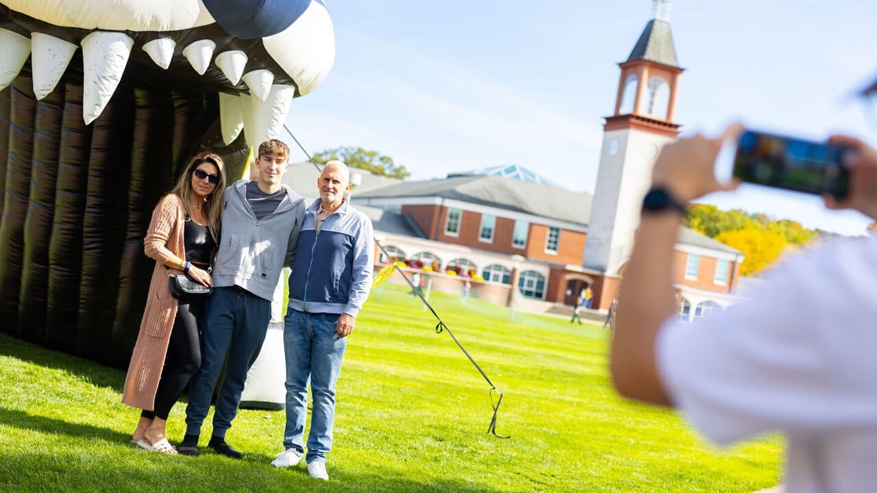 Family poses in front of an inflatable bobcat on the quad