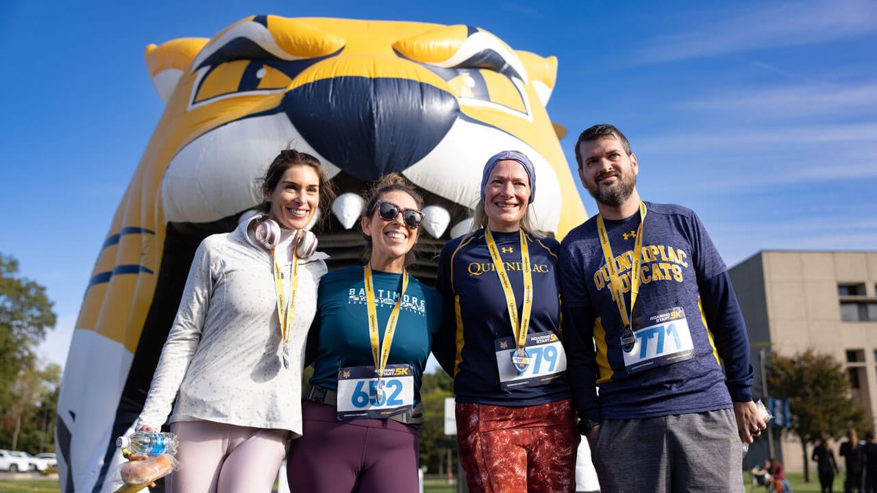 Four runners smiling with medals after finishing the 5K