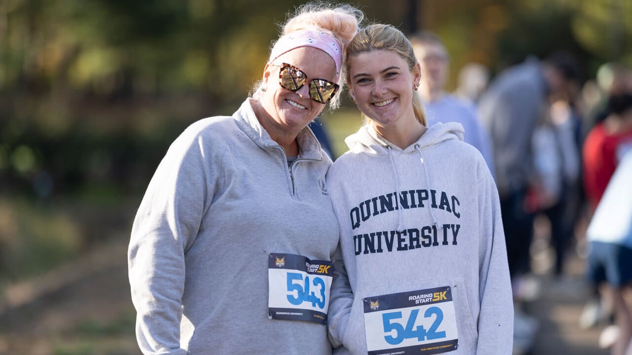 Adult and student runner smile before starting the race