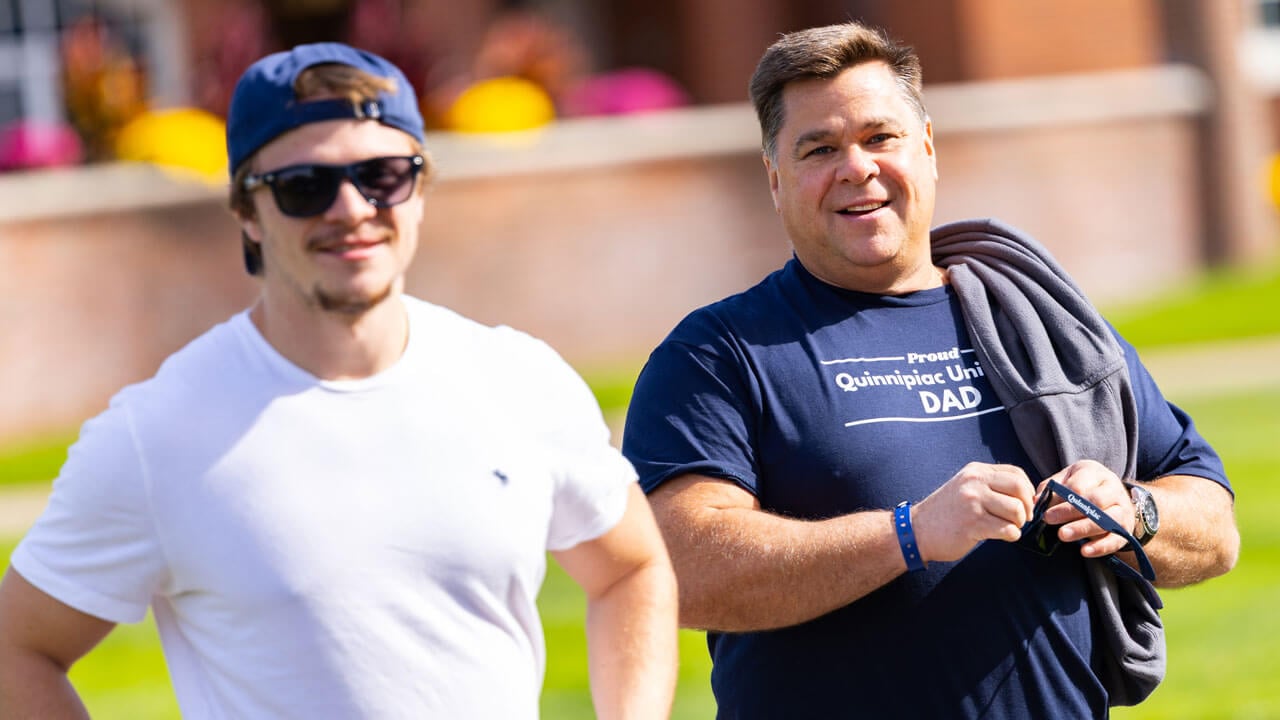 Dad and son stand together on the quad