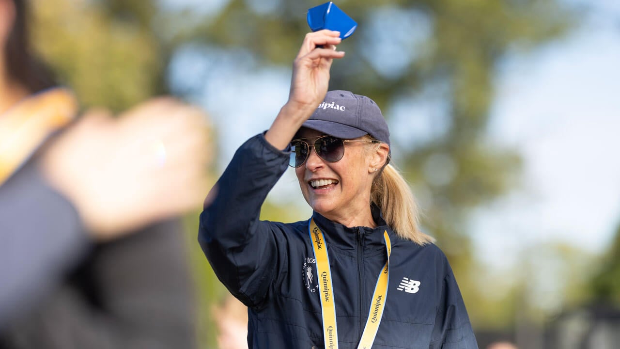 President Hardin cheering on the runners with cowbell in hand and medal around neck