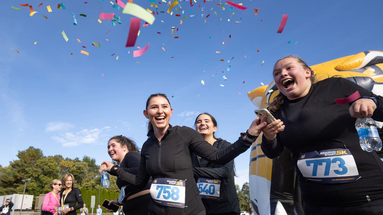 Student runners cheering with excitement and confetti after finishing the 5k
