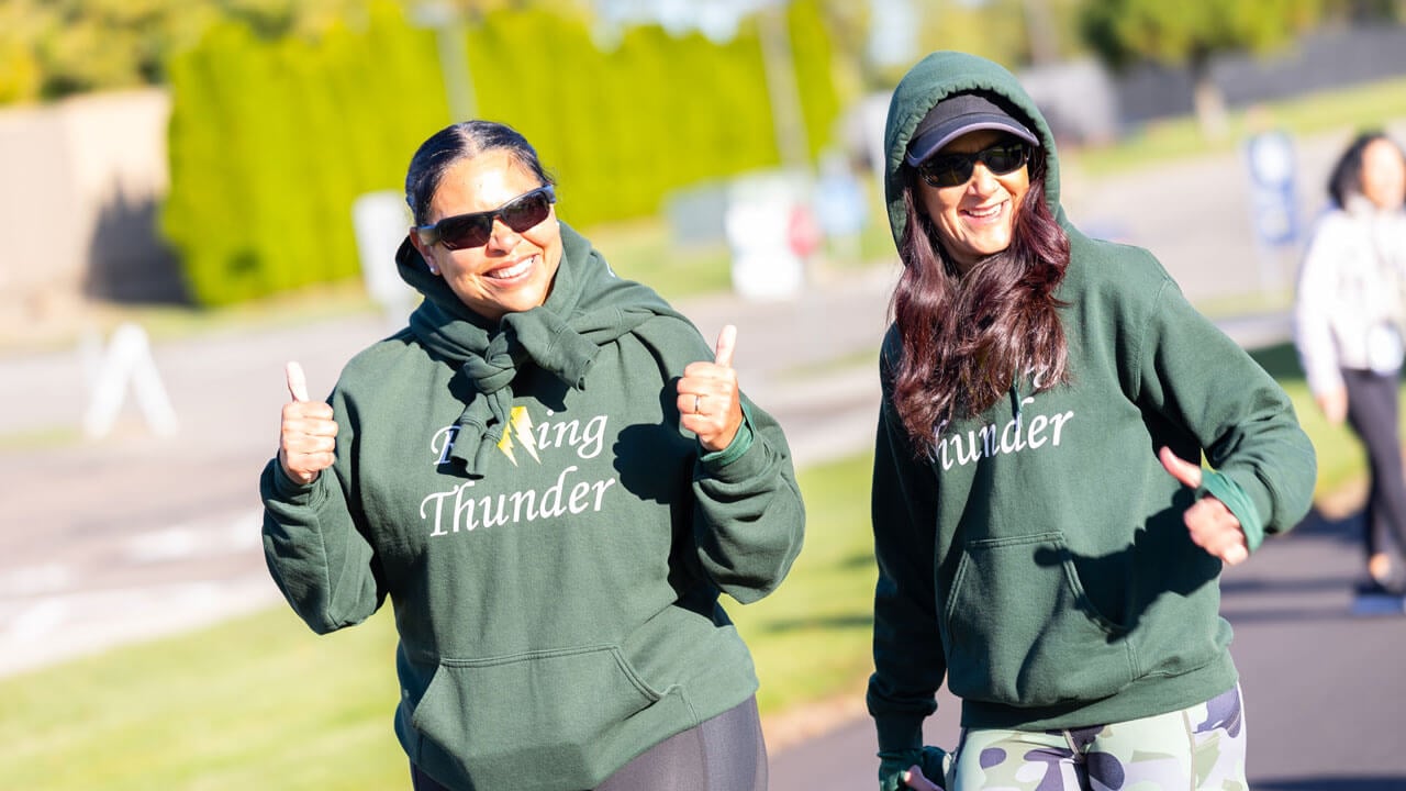 Two runners holding a thumbs up expression with smiles