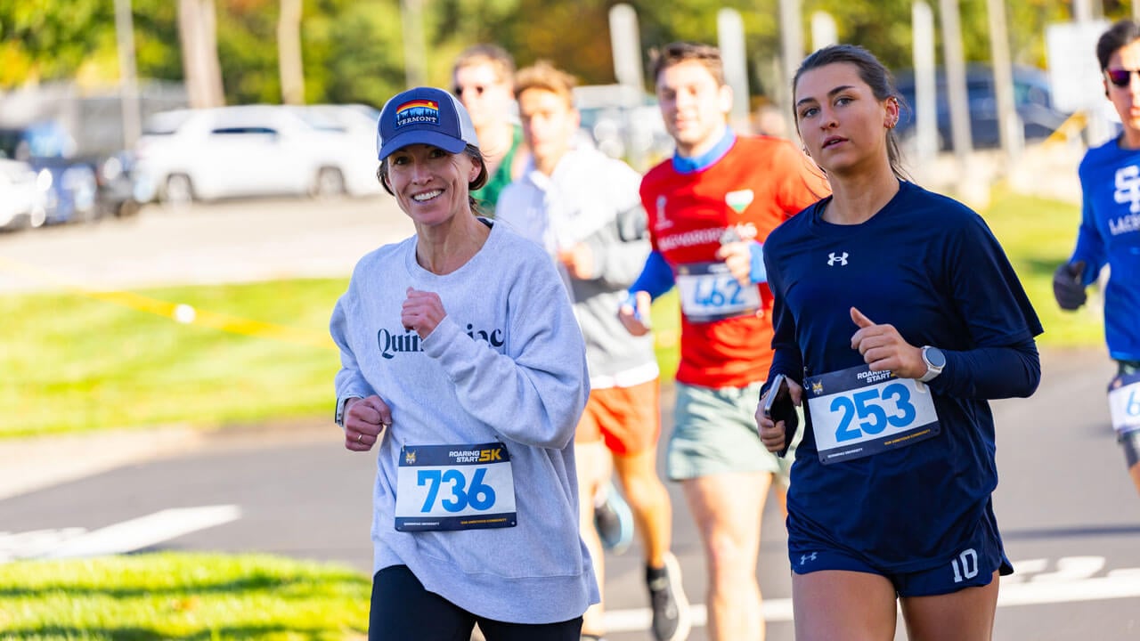 Two runners one smiling and one looking focused during the race