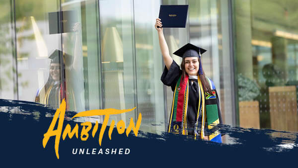 Gabriela Alvares stands in her cap and gown holding her diploma over her head.
