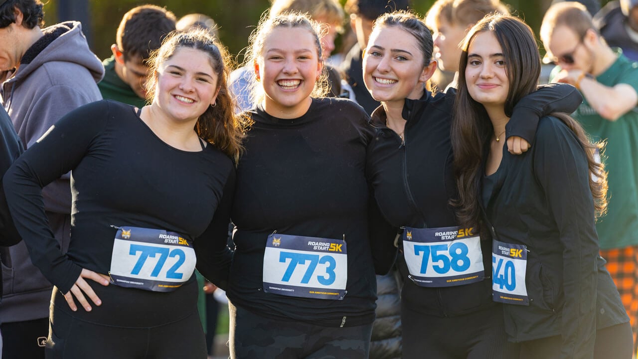 Four runners smiling for a picture before race starts