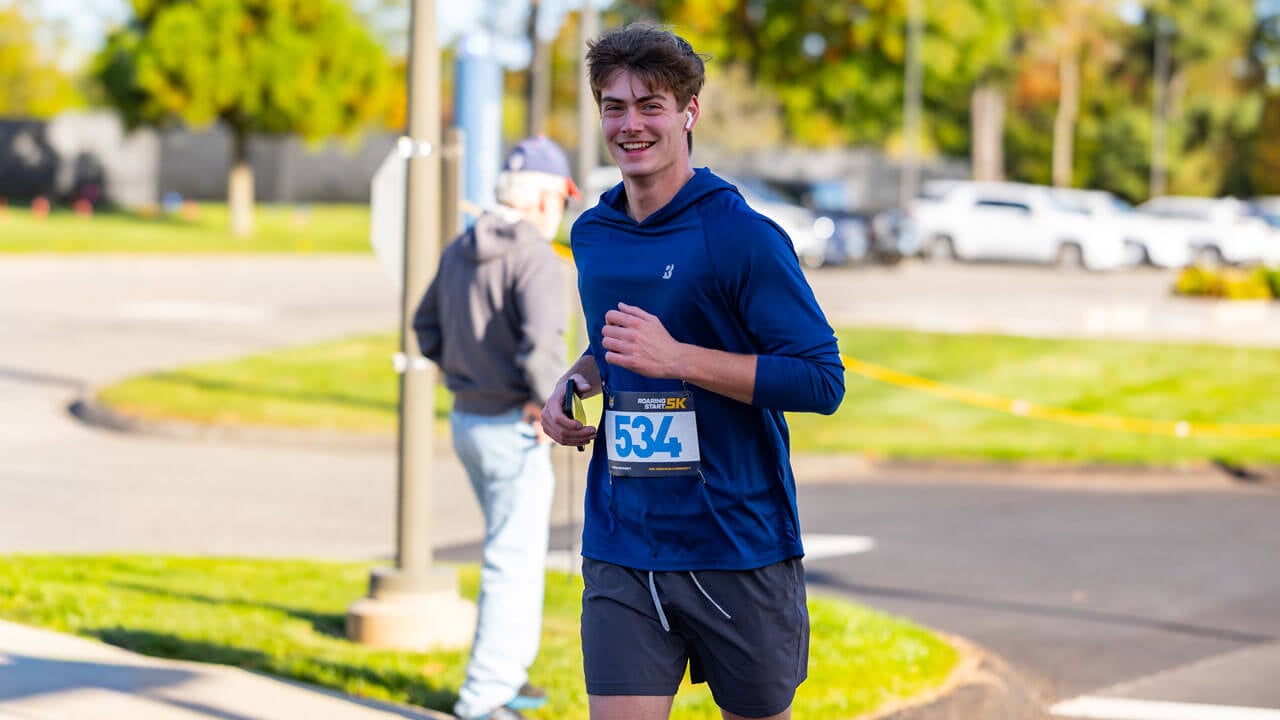 Smiling runner with headphones on and phone in hand during the race