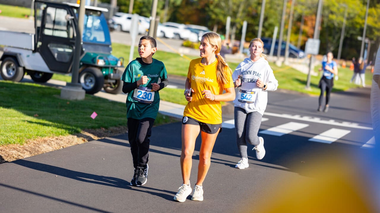 Adult runner smiles while child runner looks determined to complete the race