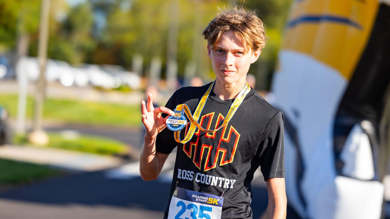 5k runner holding up medal with pride after finishing the race