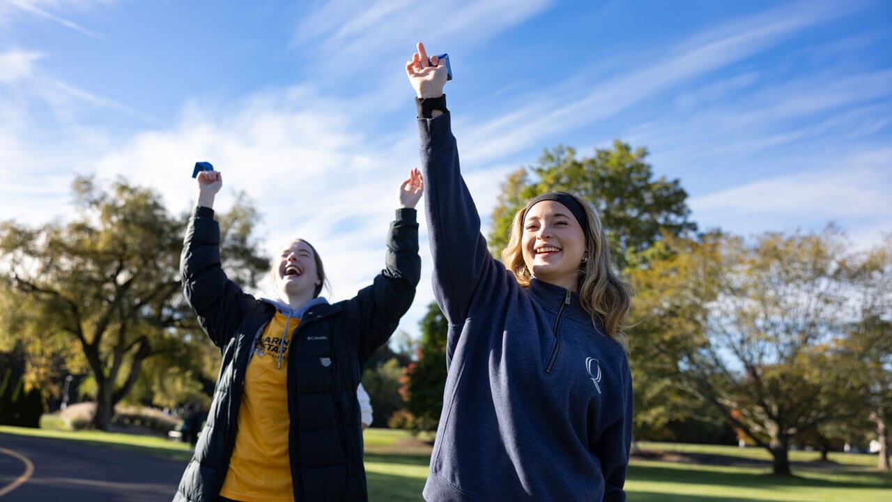 Two students cheer on racers