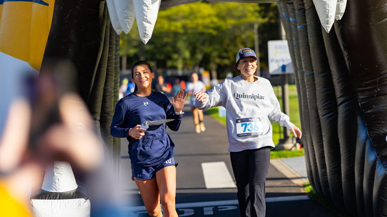 Runners finishing a high-five while running through the Bobcat head