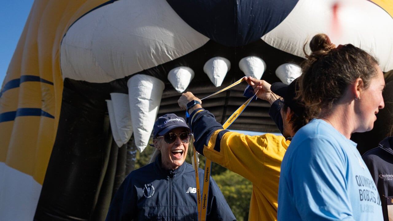 President Hardin finishing the race while Jamie Deloma awards with a medal