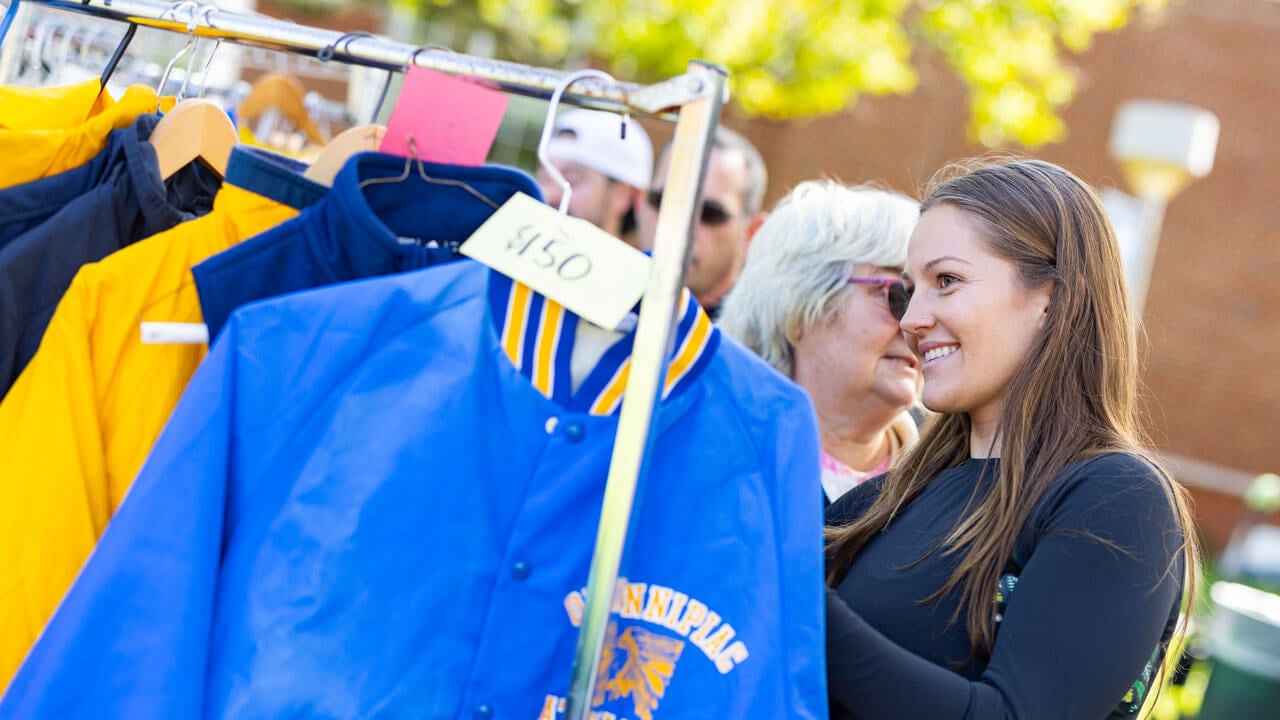 Student happily looking at Quinnipiac gear on a rack