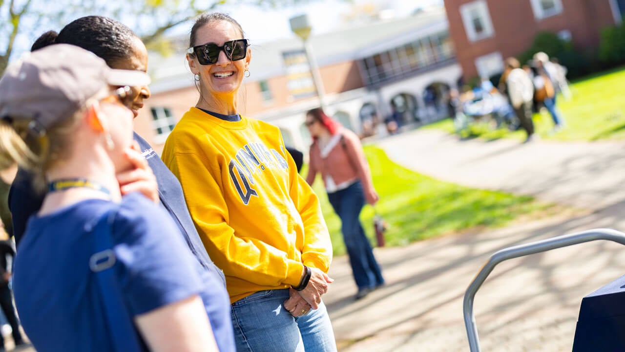 Woman smiles in bobcat gear as she looks at friends