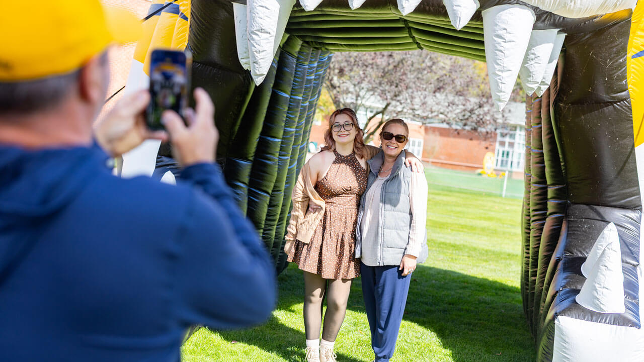 Mom and daughter smile in front of inflatable bobcat