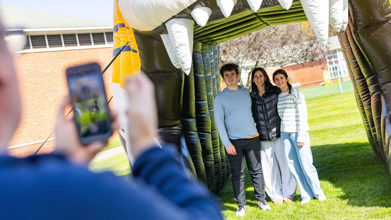 Family of three smiles in front of an inflatable bobcat