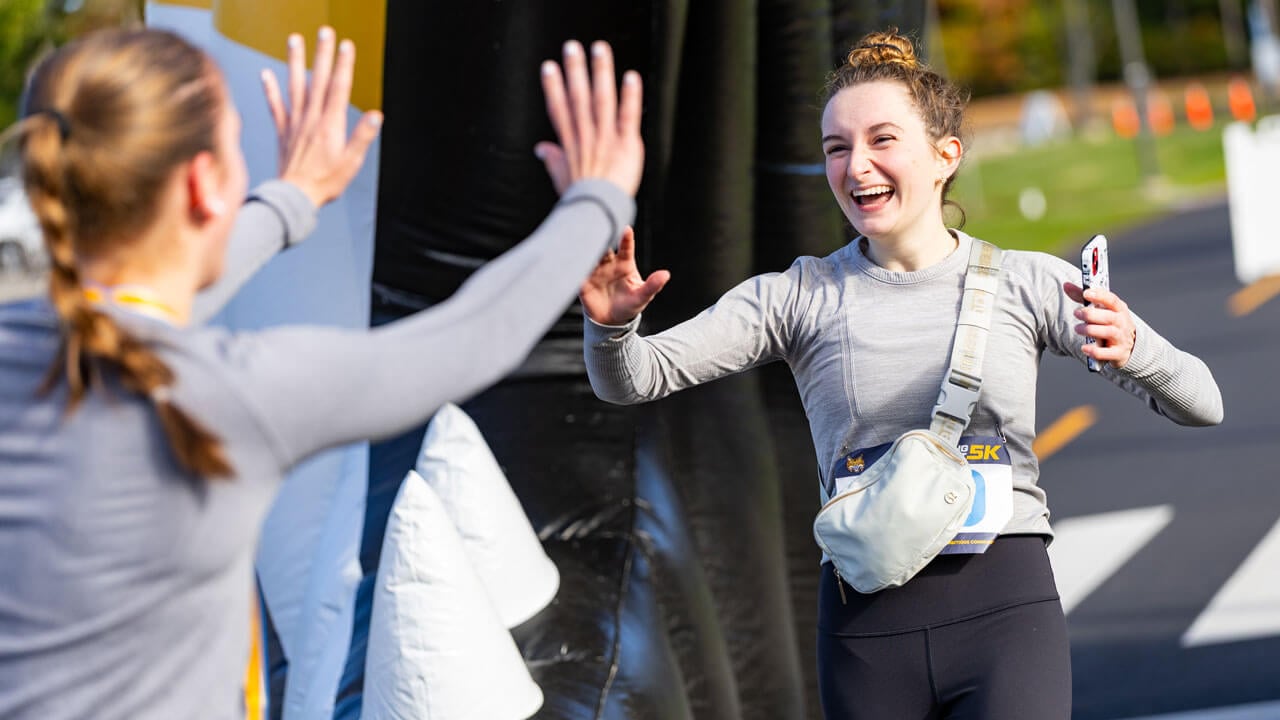 Runner finishes race with a smile while friend is waiting for a high five