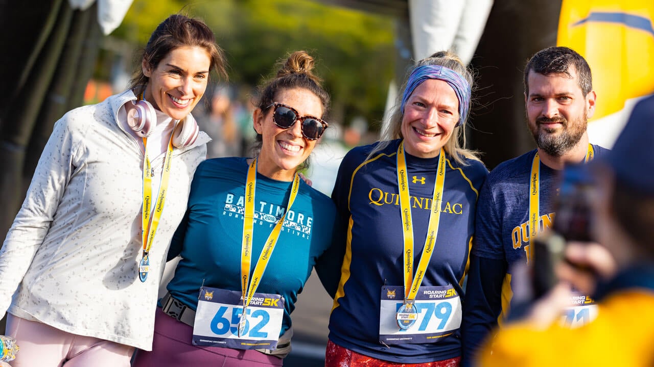 Four runners awarded medals smile for a picture after completing the race