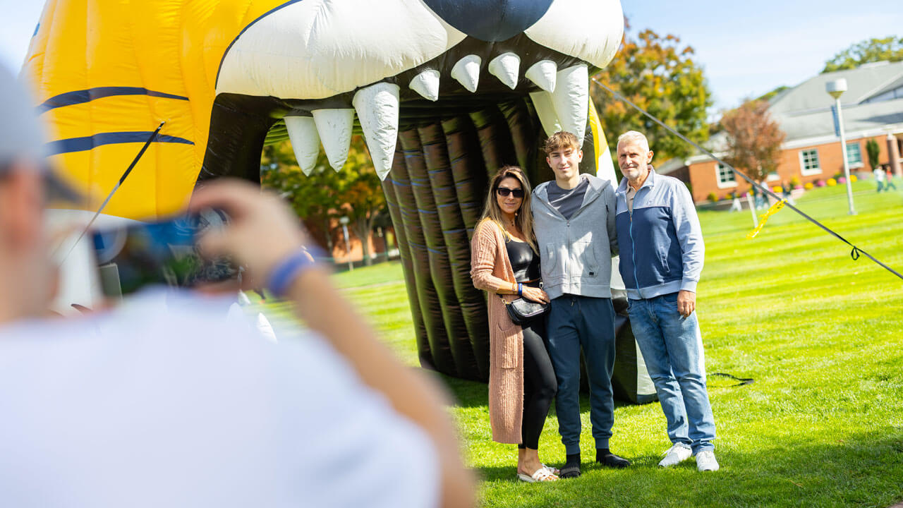 A family smiles in front of a large bobcat inflatable