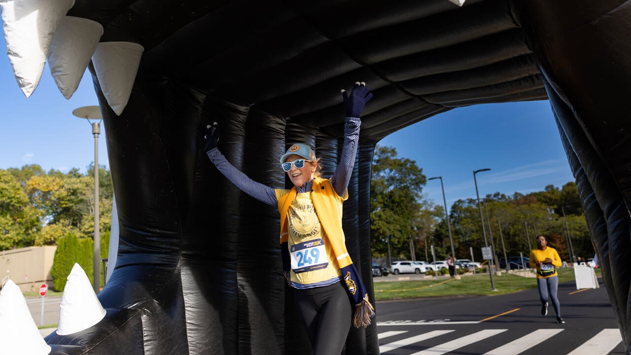 Runner celebrates as they finish the race through the Bobcat head