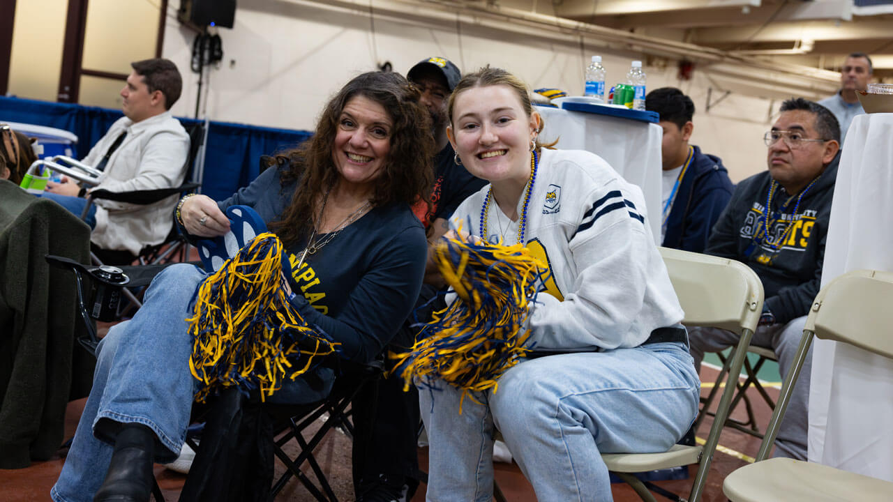 Two individuals smiling while holding bobcat gear