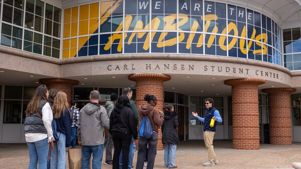 A tour guide leads a group in front of the Quinnipiac student center