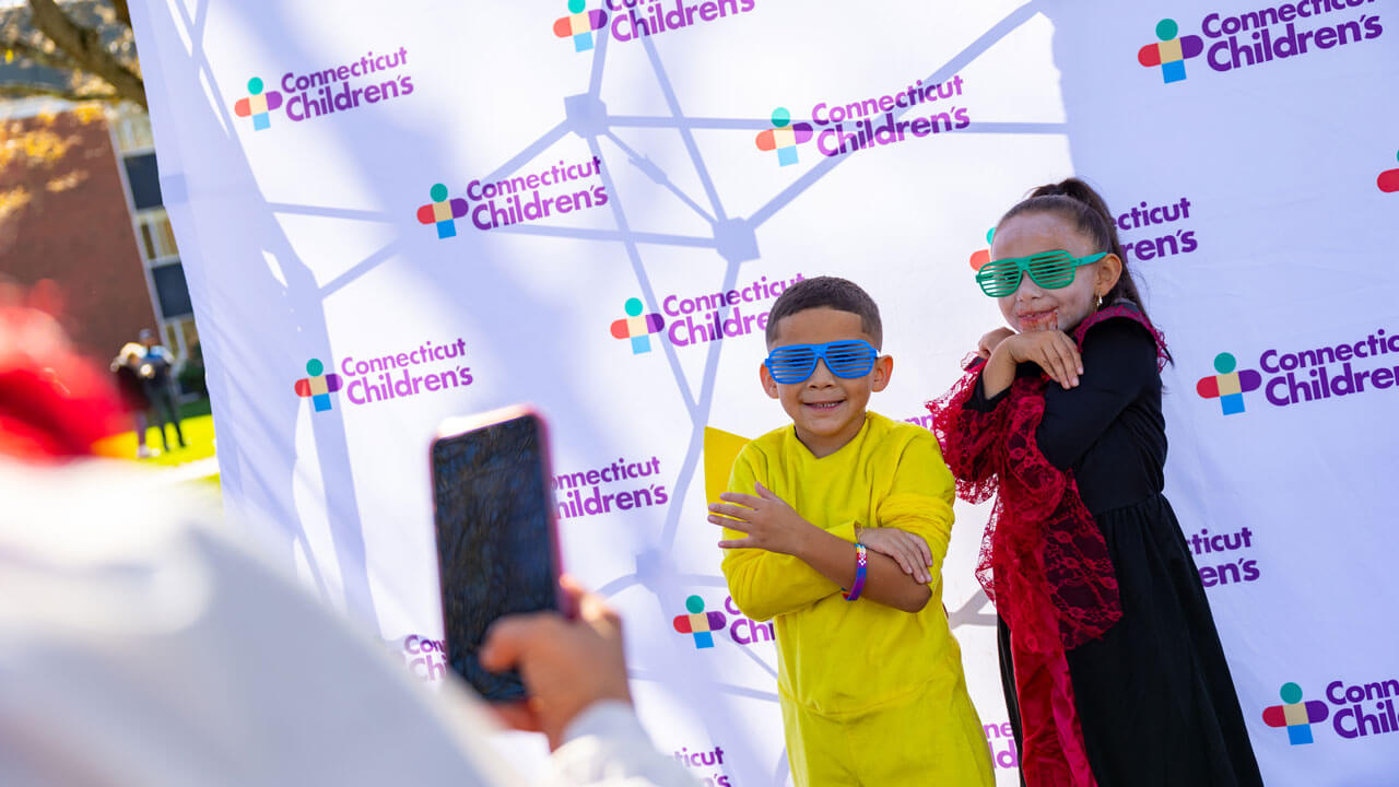 Children pose in front of a Connecticut Children's step and repeat