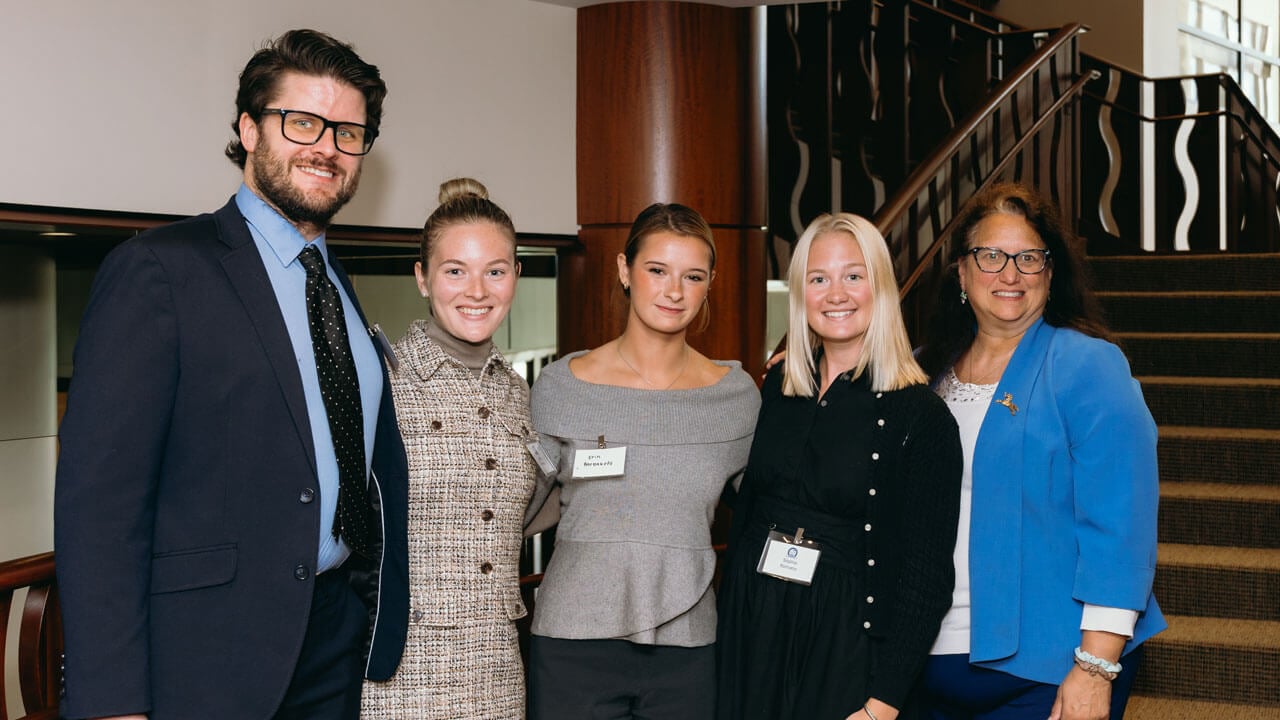 Group of five smile together and pose for a picture