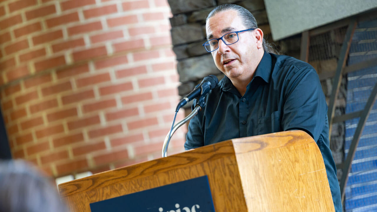 Presenter standing at podium speaking at the indigeneity initiative teach in