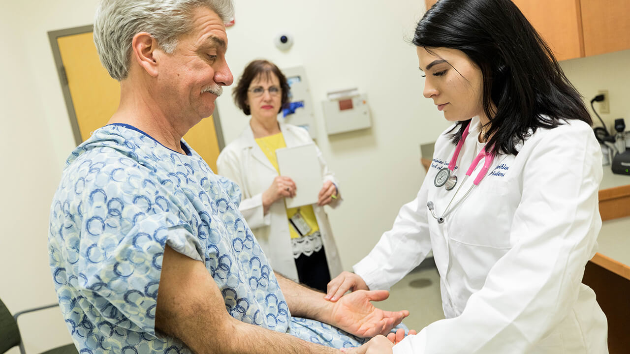 A doctor of nursing practice student performs an exam on an actor portraying a patient in the Standardized Patient Assessment Center on the North Haven Campus.