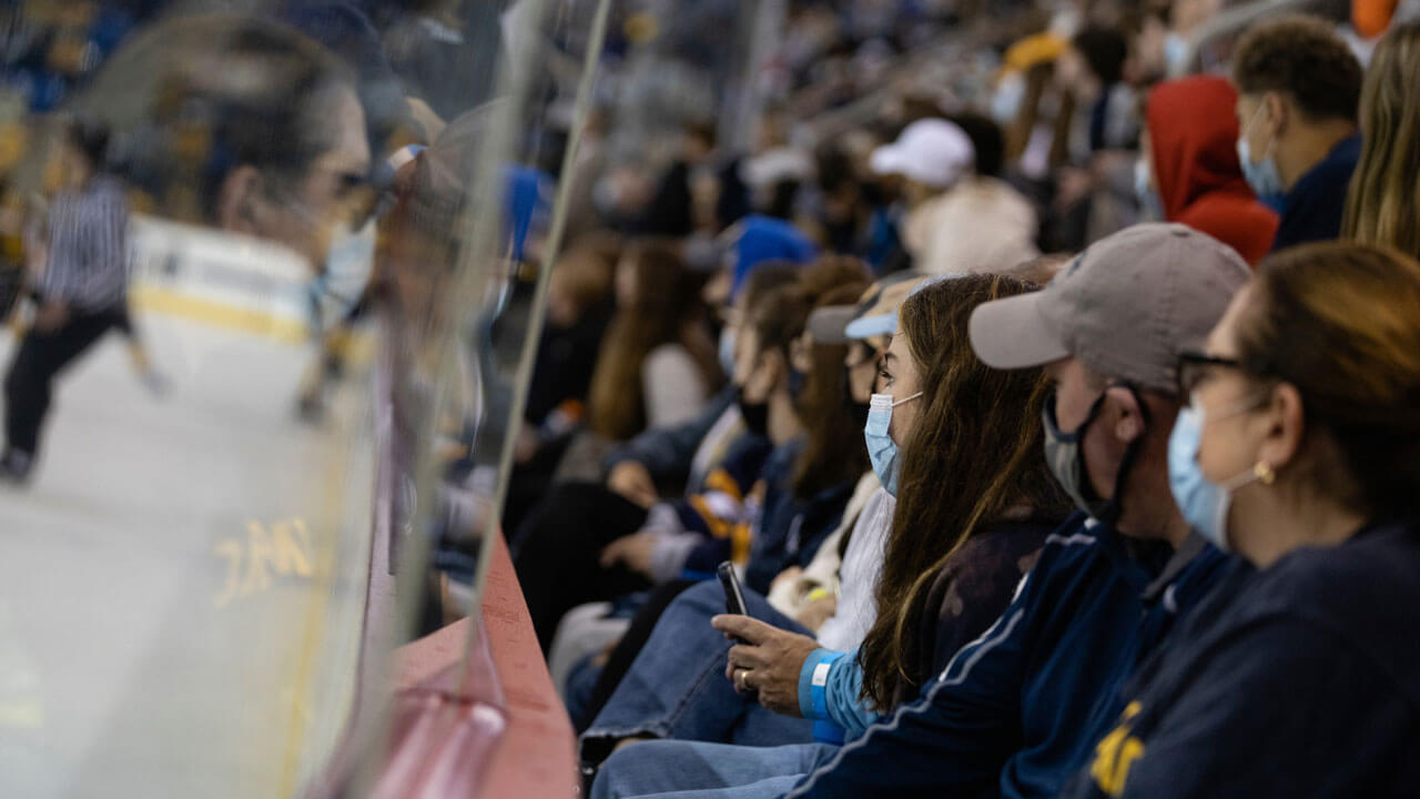 Students and parents lined up in front of the ice while watching a hockey game