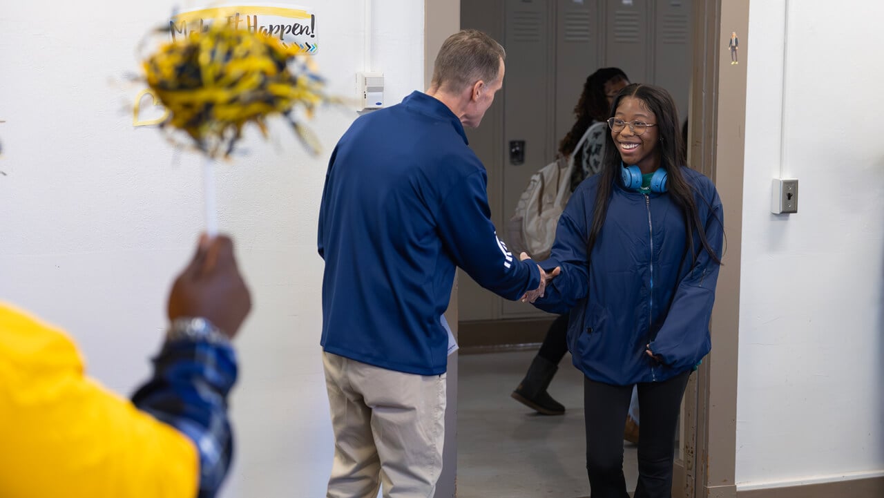 A new student smiles and shakes hands with Tom Ellett