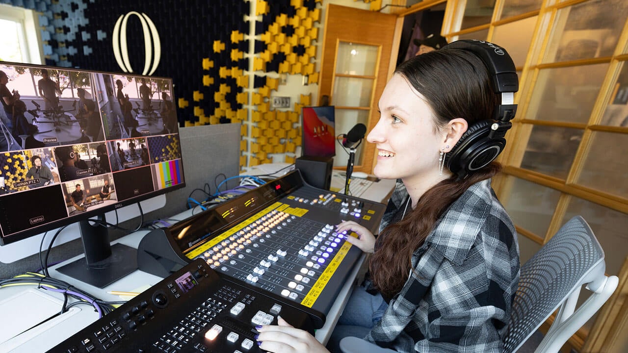 Student at the sound board in the School of Communications Podcast Studio