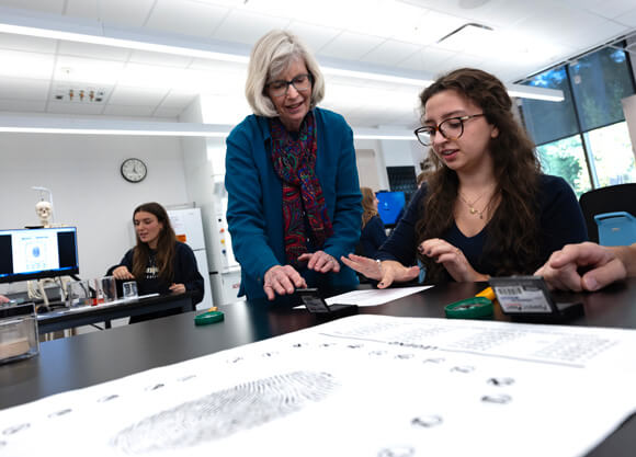 Students work on a fingerprinting lesson with a professor watching over them