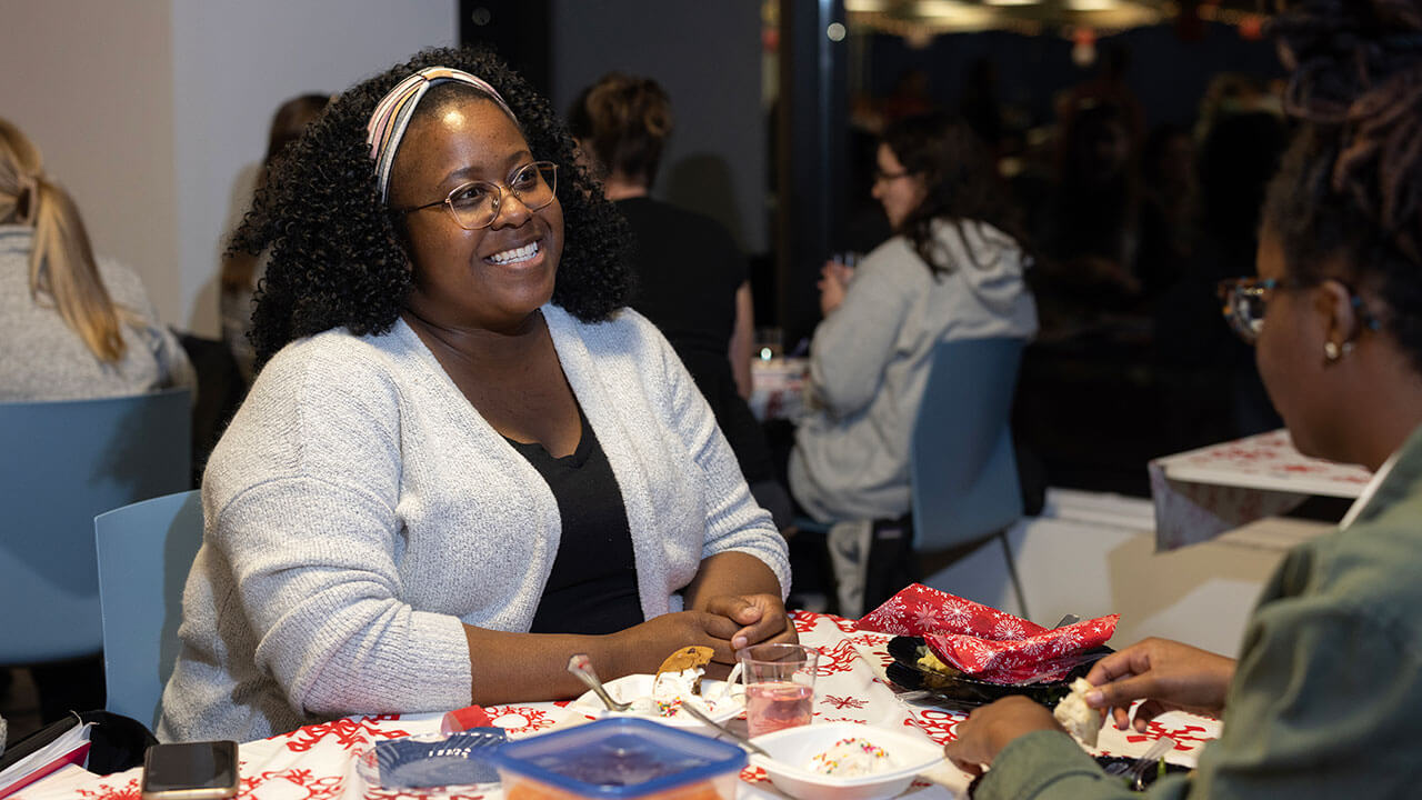 Two women smile and enjoy each others company while eating dinner