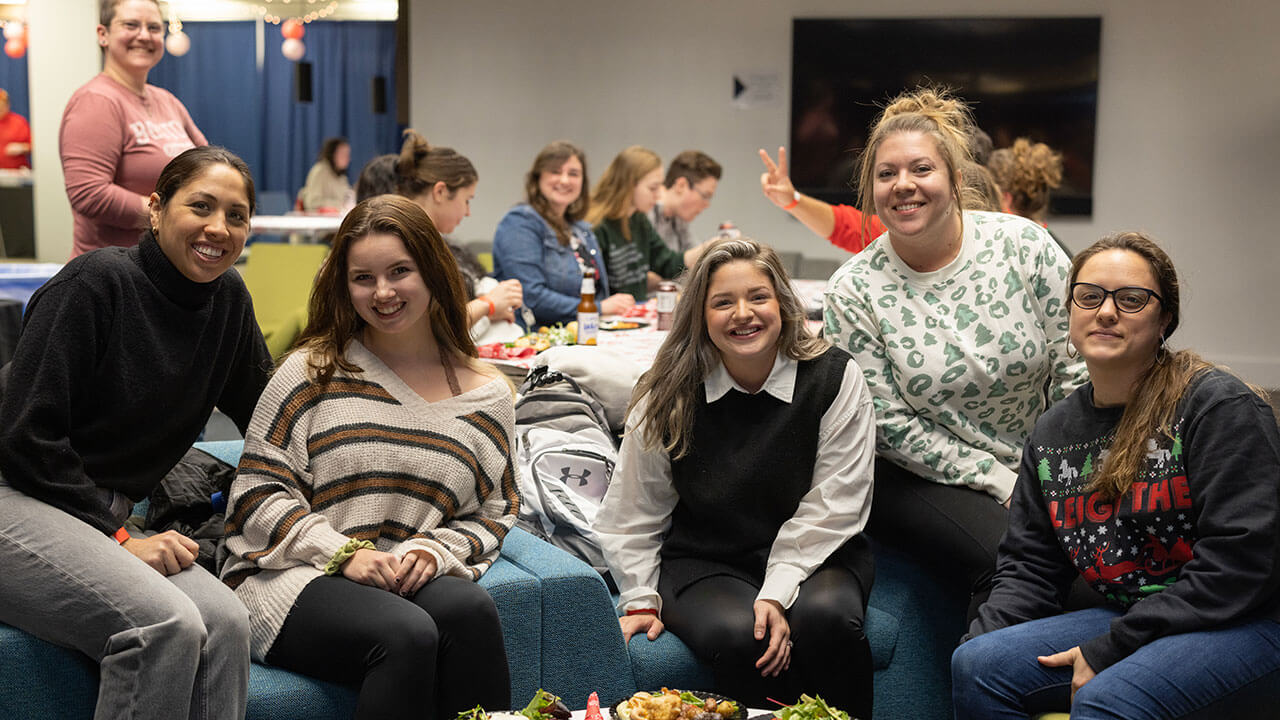 A group of graduate students smile for a photo as they celebrate the holiday season