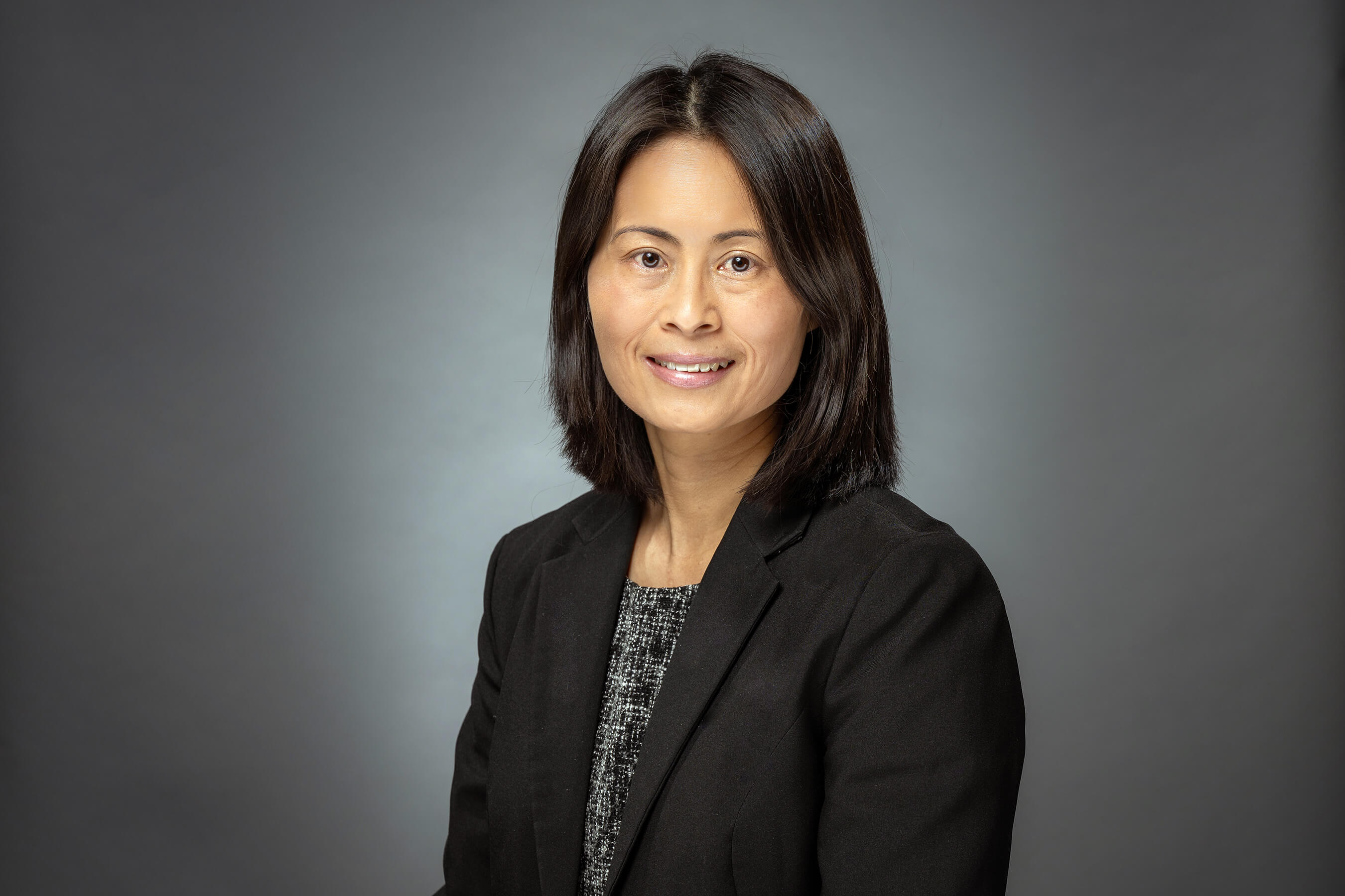 Anita Lee smiles for a headshot wearing a blazer.