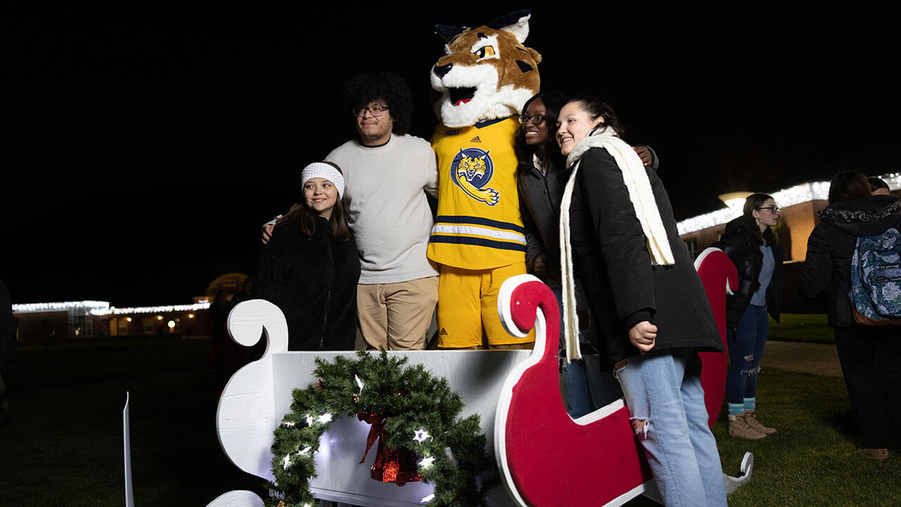 Students take a photo with Boomer in a holiday sleigh