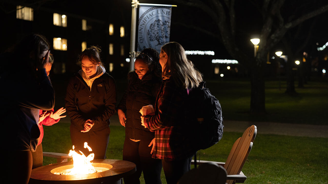 Students sit around the fire pits